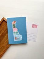 A postcard with an illustration of Delaware state in a colorful artistic style on a blue background.
