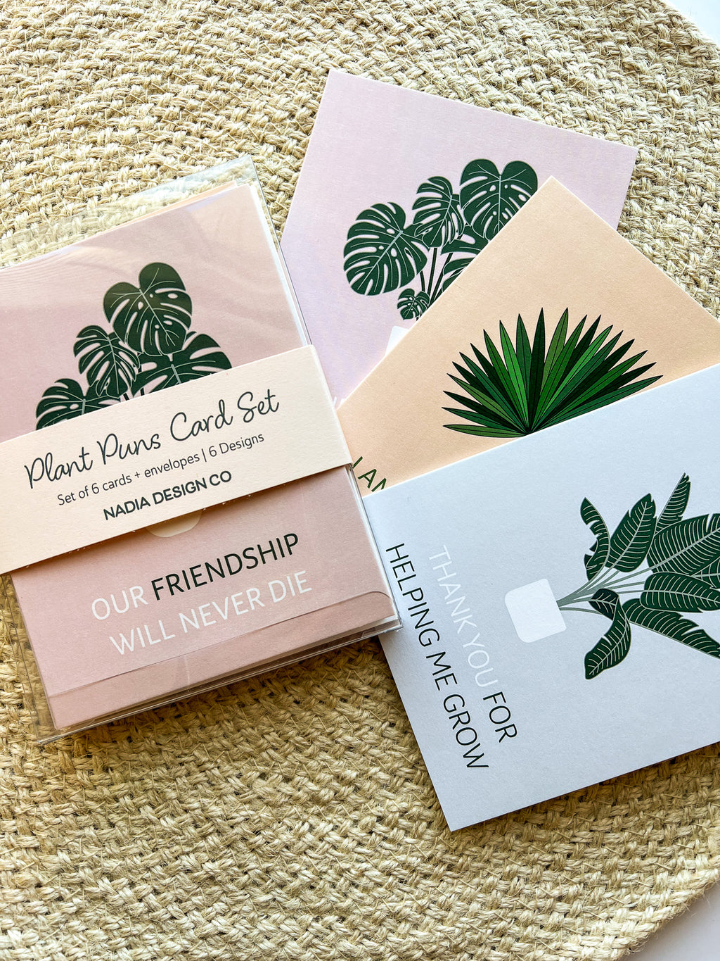 A set of six illustrated greeting cards with various houseplants and punny captions related to plants displayed on a wooden surface.