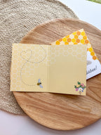 Yellow card with bee design on a wooden surface