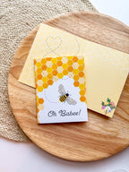 Greeting card with honeycomb design and bee illustration on a wooden surface
