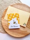 Greeting card with honeycomb design and bee illustration on a wooden surface