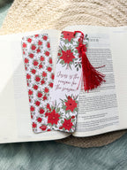 poinsettia Floral Christian bookmark with text" Jesus is the reason for the season" with red tassel on a textured surface