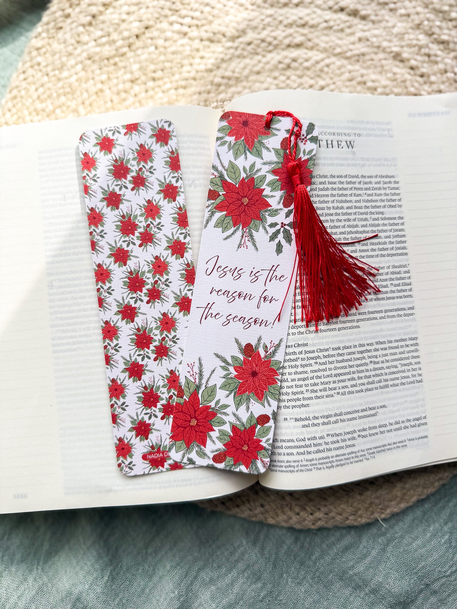 poinsettia Floral Christian bookmark with text" Jesus is the reason for the season" with red tassel on a textured surface