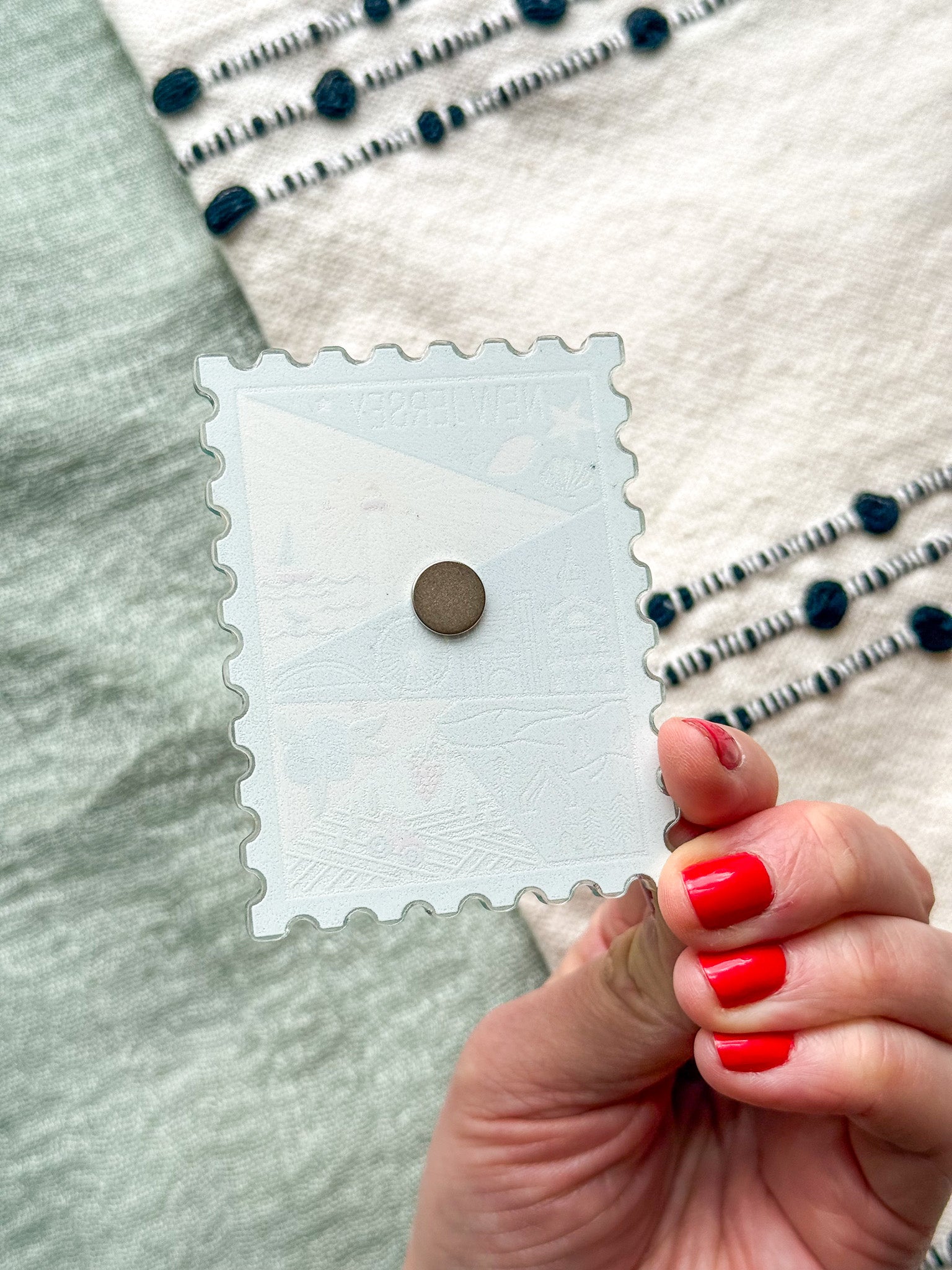 back of illustrated New Jersey Acrylic Stamp Magnet held and textured fabric behind