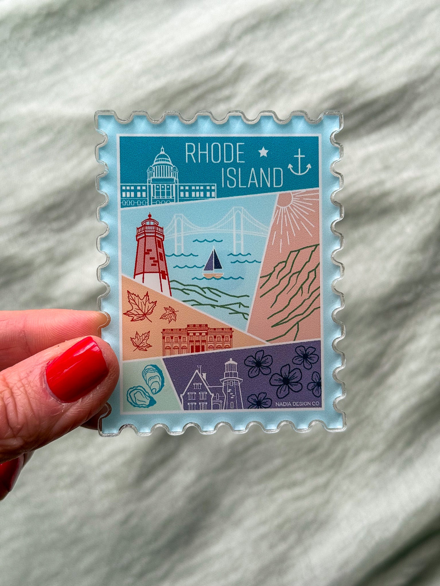 illustrated Rhode Island Acrylic Stamp Magnet held and textured fabric behind