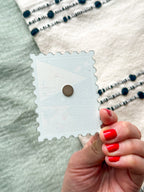 back of illustrated Rhode Island Acrylic Stamp Magnet held and textured fabric behind