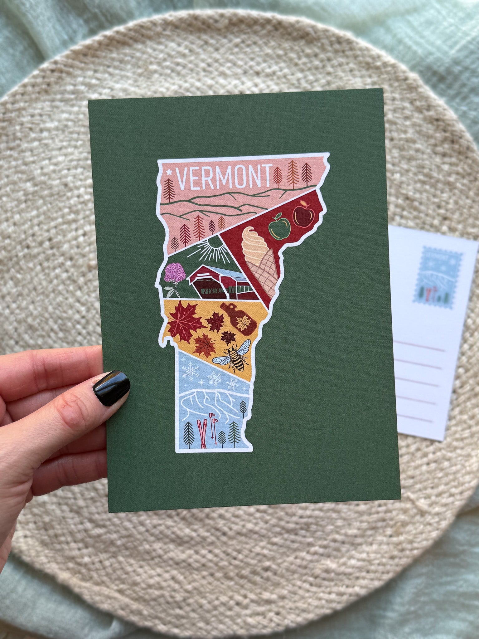 postcard with an illustration of Vermont on a green background held by a hand.