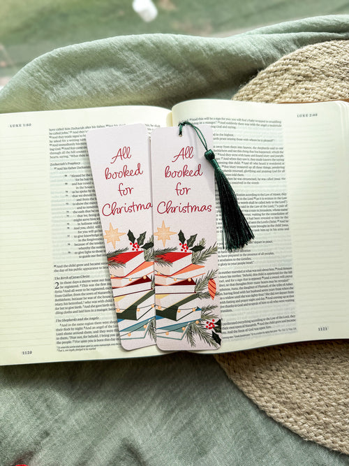 Bookmarks with Christmas design on an open book, placed on a textured surface.