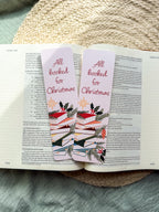 Christmas-themed pun "All Booked for Christmas" bookmarks on an open book with a textured surface in the background.
