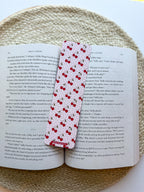 Open book with a cherry pattern bookmark featuring red cherries on a woven surface.