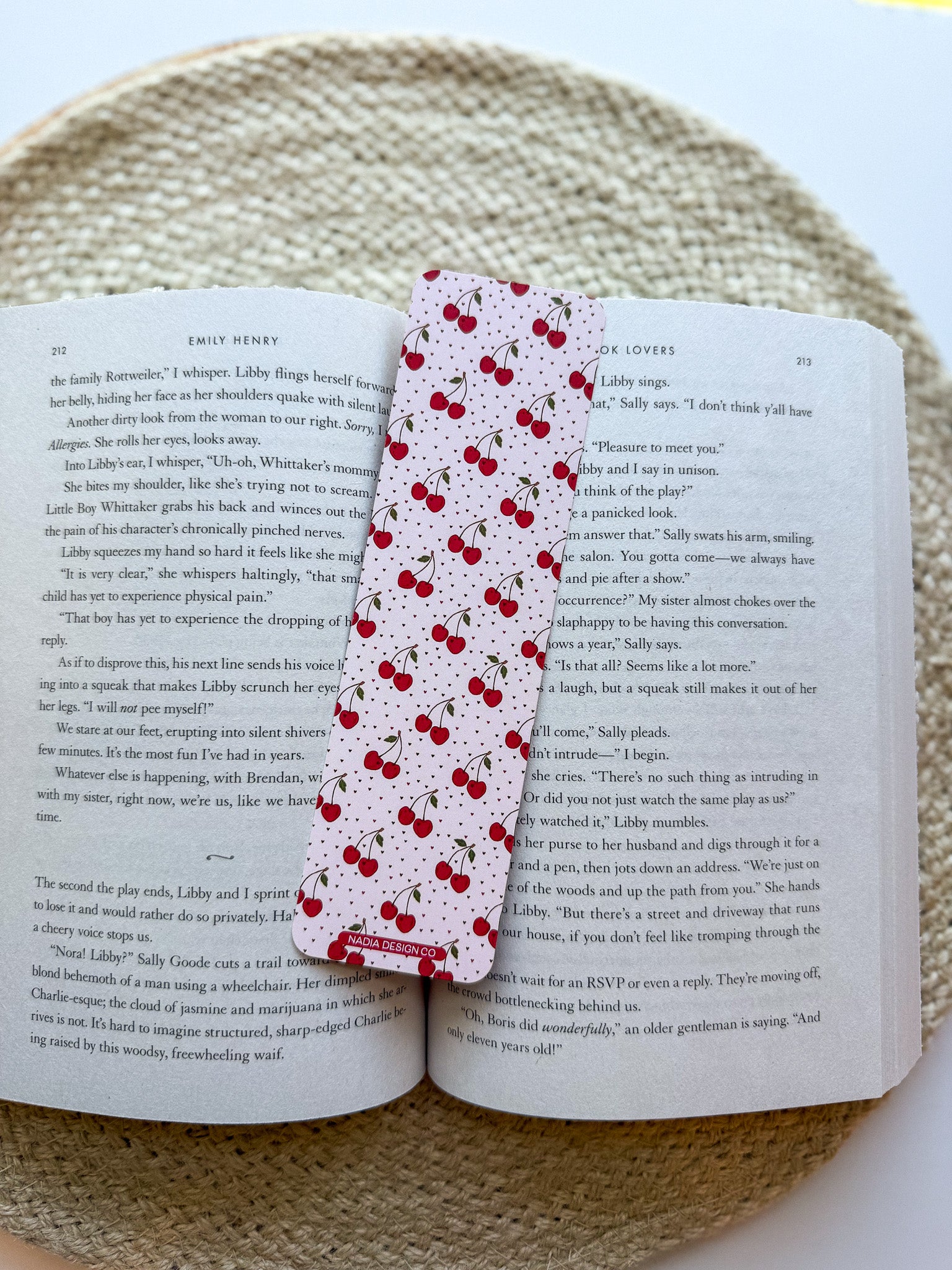 Open book with a cherry pattern bookmark featuring red cherries on a woven surface.