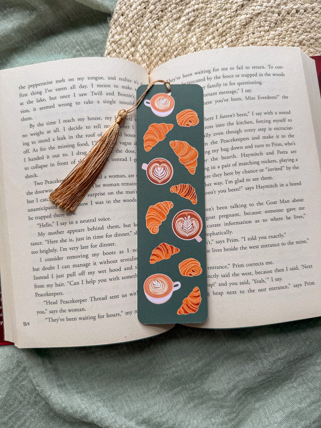 Bookmark with croissant and coffee design with a tassel and on an open book