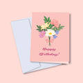 A greeting card with a floral birthday bouquet illustration and the text 'Happy Birthday!' on the front, accompanied by a white envelope, against a pink background.