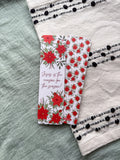 poinsettia Floral Christian bookmark with text "Jesus is the reason for the season" on a textured surface