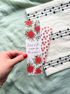 poinsettia Floral Christian bookmark with text" Jesus is the reason for the season" on a textured surface