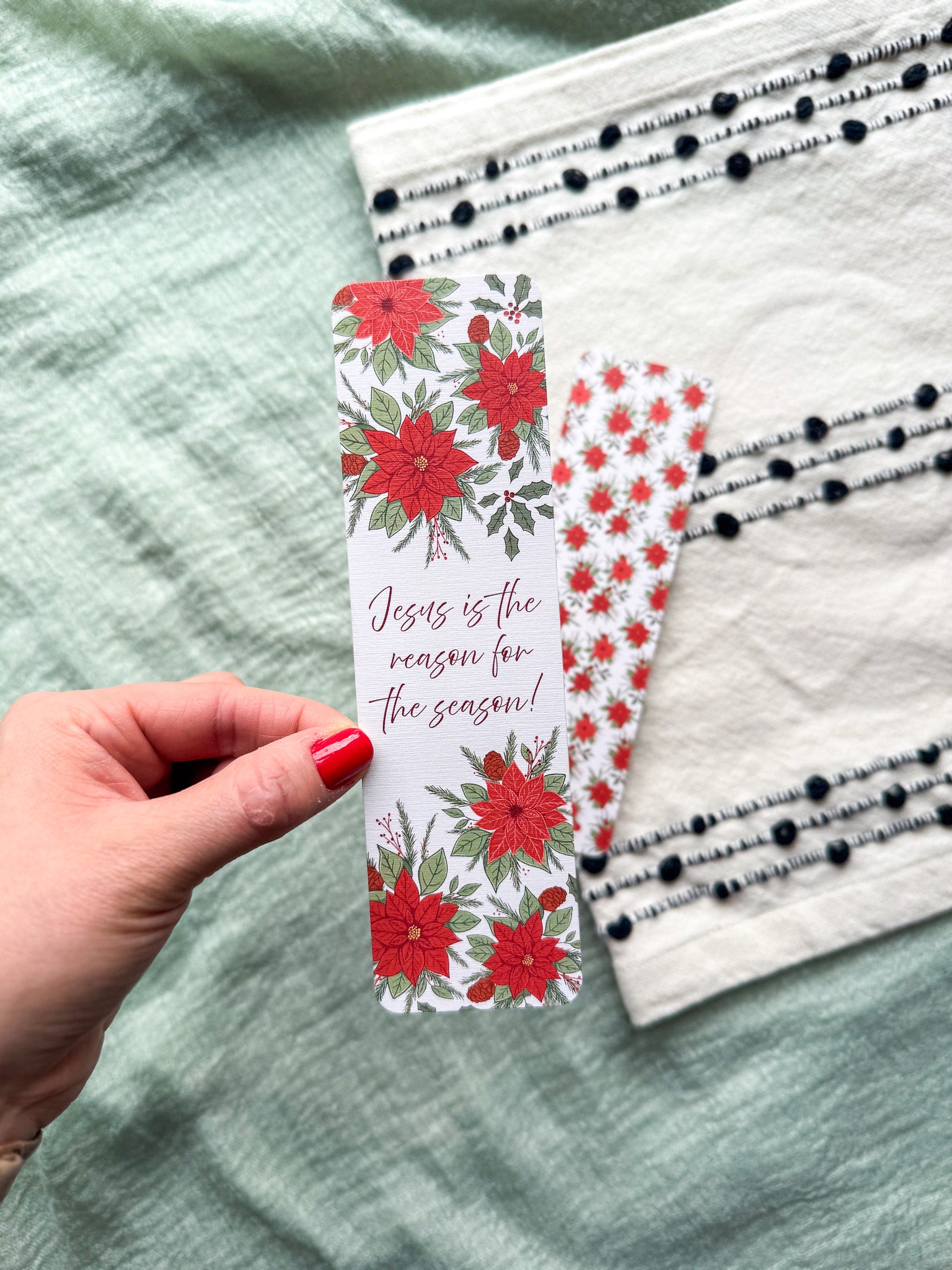 poinsettia Floral Christian bookmark with text" Jesus is the reason for the season" on a textured surface