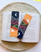 Two colorful bookmarks with mountain designs on an open book.