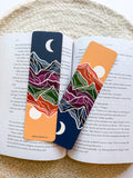 Two colorful bookmarks with mountain designs on an open book.