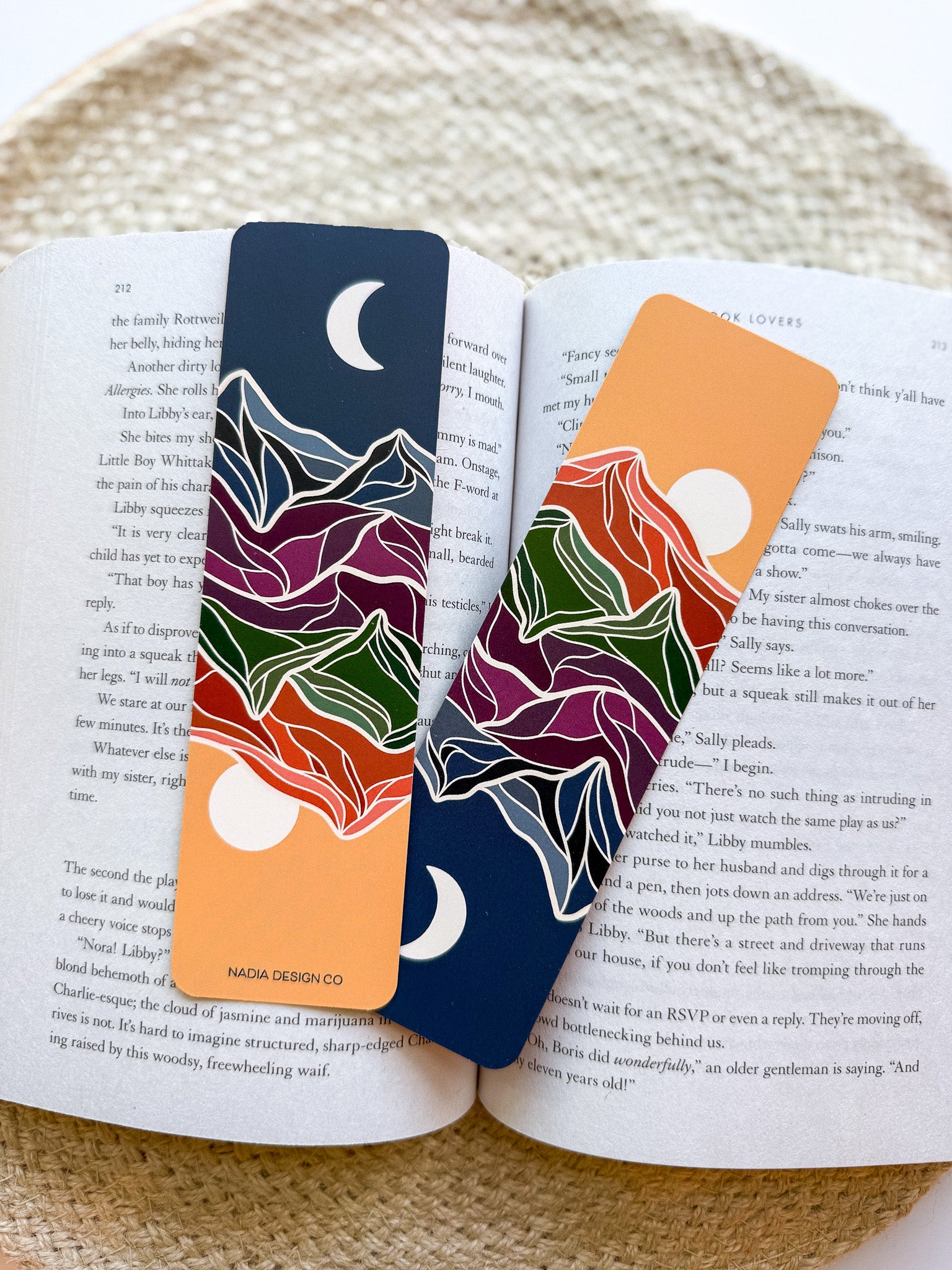 Two colorful bookmarks with mountain designs on an open book.