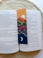 Colorful mountain-themed bookmark on an open book