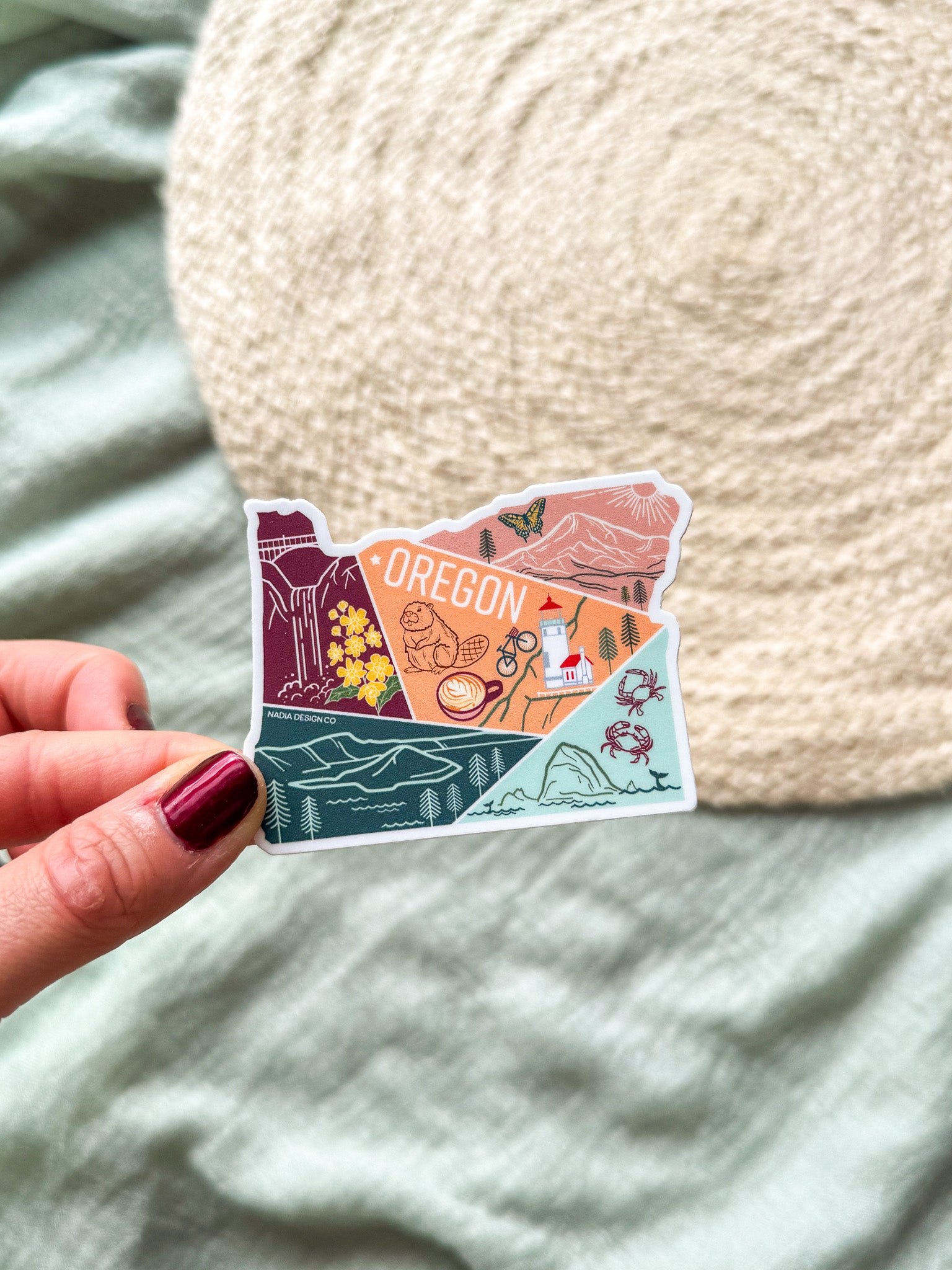 Colorful illustrated sticker shaped like the state of Oregon on a textured surface