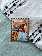 Colorful Vermont-themed stamp design sticker on a textured fabric background