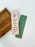 Two bookmarks with one having a green floral pattern and the other a beige grennery design, both with text on them, placed in a clear poly sleeve.