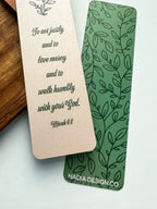 Two bookmarks with one having a green floral pattern and the other a beige grennery design, both with text on them, placed in a clear poly sleeve.