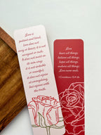 A bookmark with a rose illustration and a red tassel, placed on an open book.
