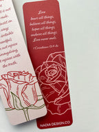 A bookmark with a rose illustration and a red tassel, placed on an open book.