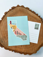 A colorful postcard featuring an illustration of California's landscape, including mountains, a beach, and iconic symbols like palm trees and a sailboat.