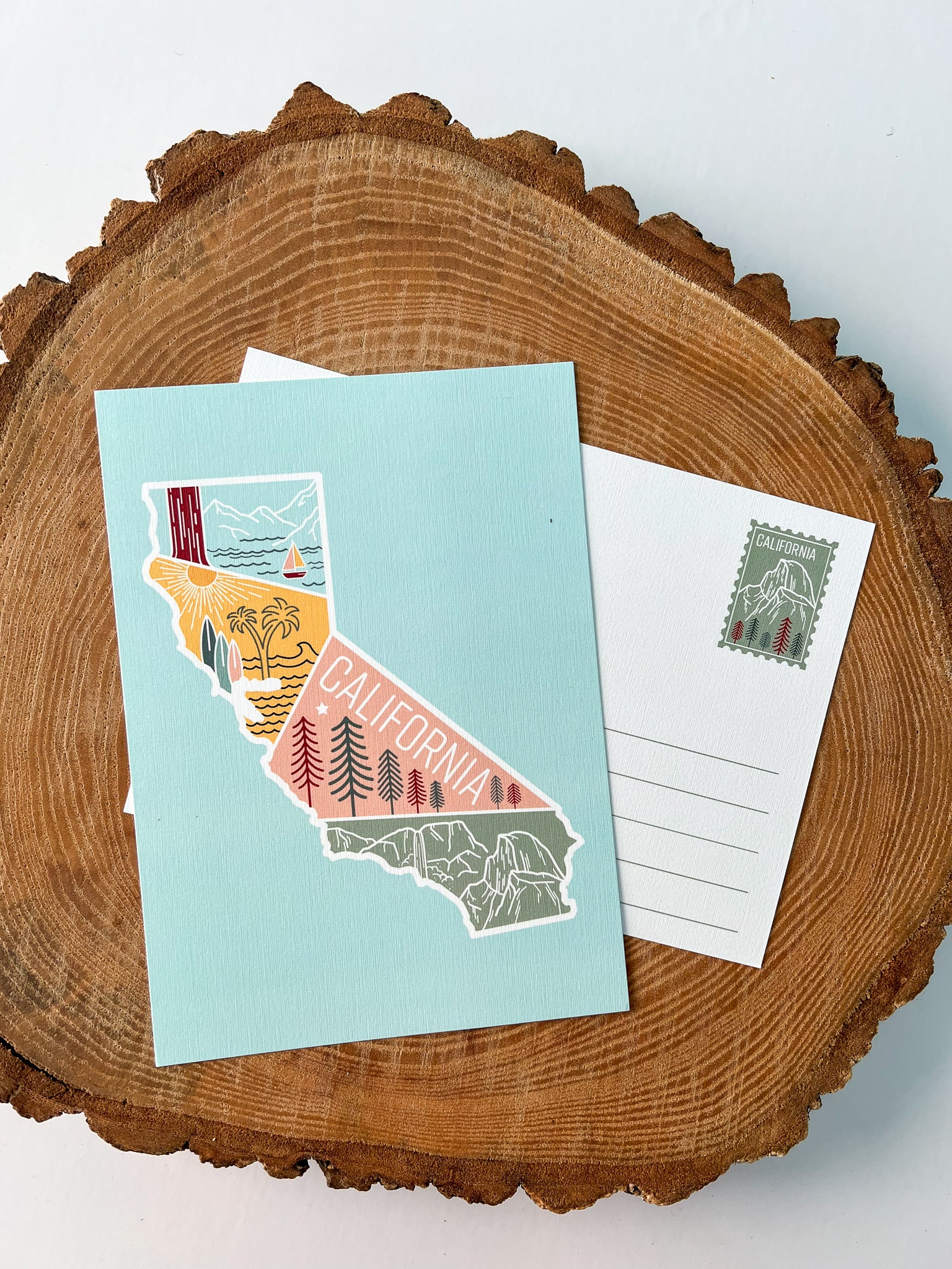 A colorful postcard featuring an illustration of California's landscape, including mountains, a beach, and iconic symbols like palm trees and a sailboat.