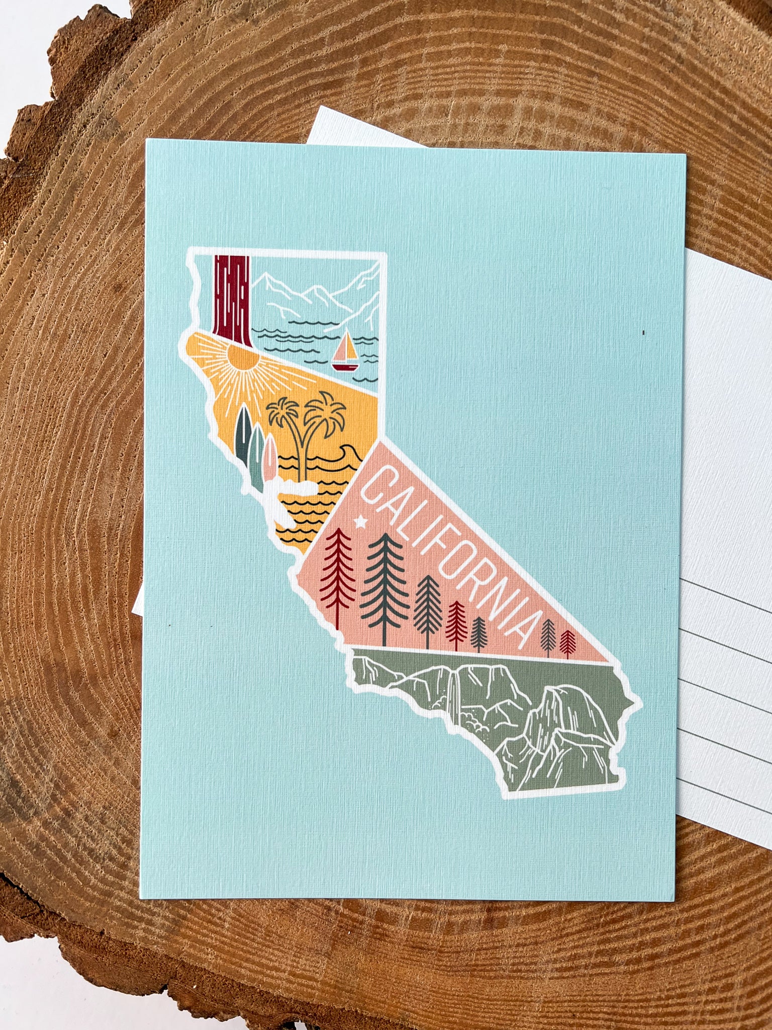 A colorful postcard featuring an illustration of California's landscape, including mountains, a beach, and iconic symbols like palm trees and a sailboat.