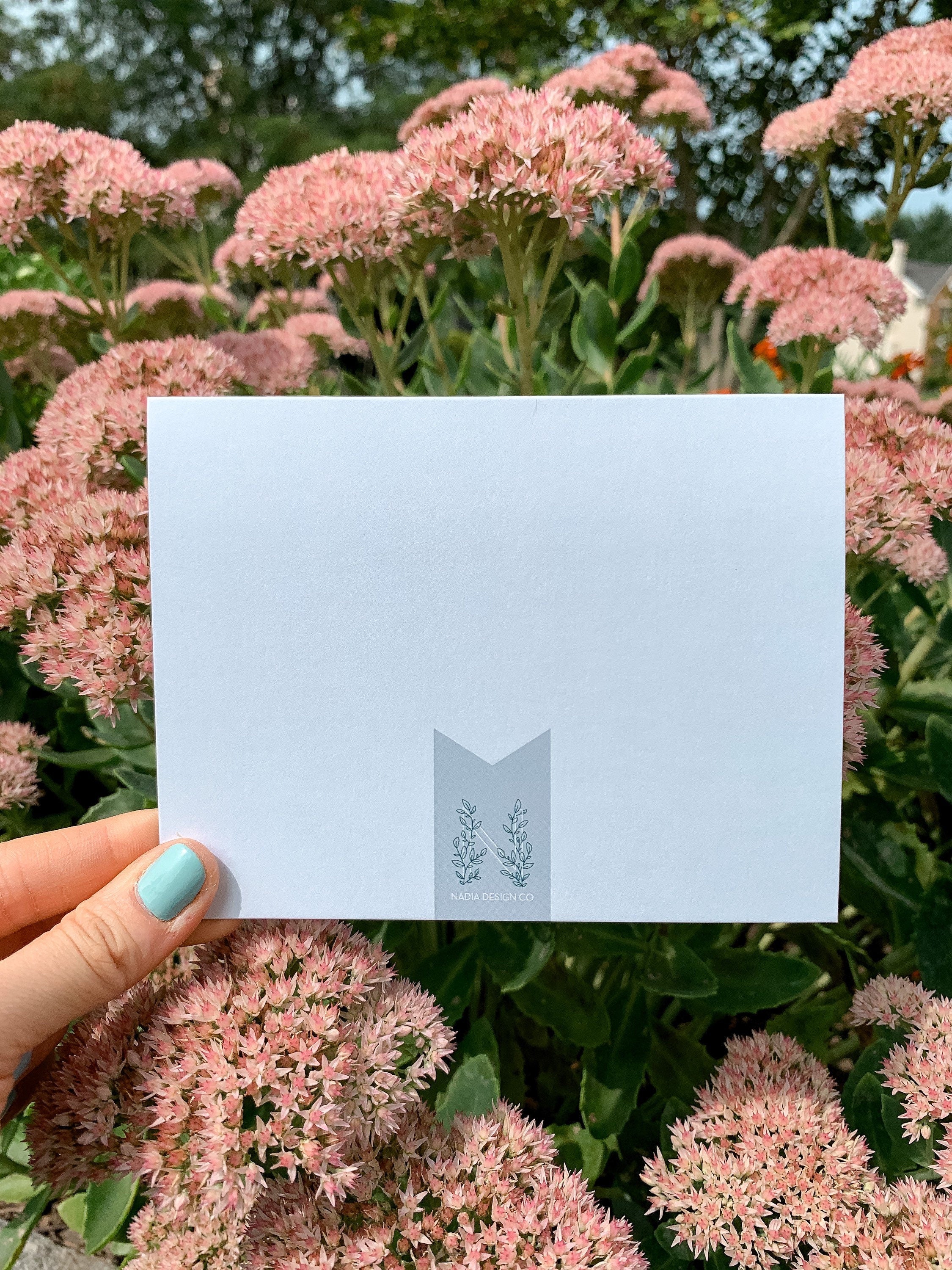 background of greeting card with illustrations of three cacti in pots and the text 'HOPE YOUR BIRTHDAY IS ON POINT!' on it, placed on a wooden surface with leaves around.