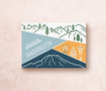 A postcard featuring illustrated landscapes and iconic symbols of Washington state, including mountains and the Seattle Space Needle.
