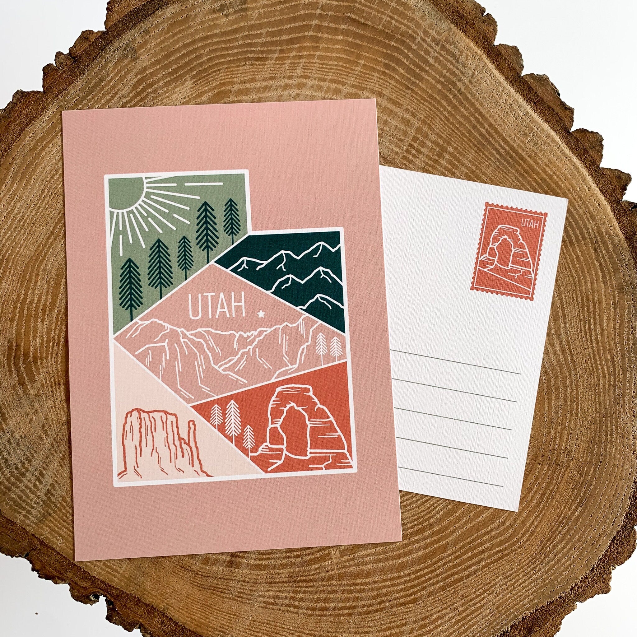 A postcard with an illustrated mountain range and the text 'UTAH' prominently featured. The design includes a mix of colors representing the landscape,