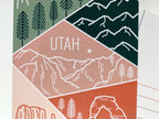 A postcard featuring a colorful illustration of Utah's landscape, including mountains and trees, with the word 'UTAH' prominently displayed.