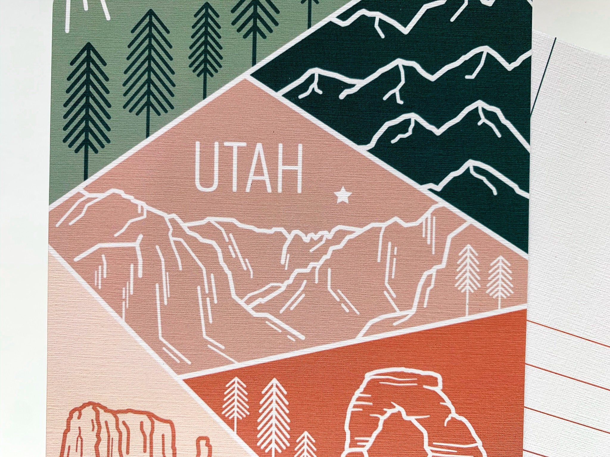 A postcard featuring a colorful illustration of Utah's landscape, including mountains and trees, with the word 'UTAH' prominently displayed.
