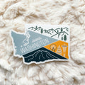 A vinyl sticker depicting a stylized map of Washington State with a mountain range, a ferry, and a city skyline.