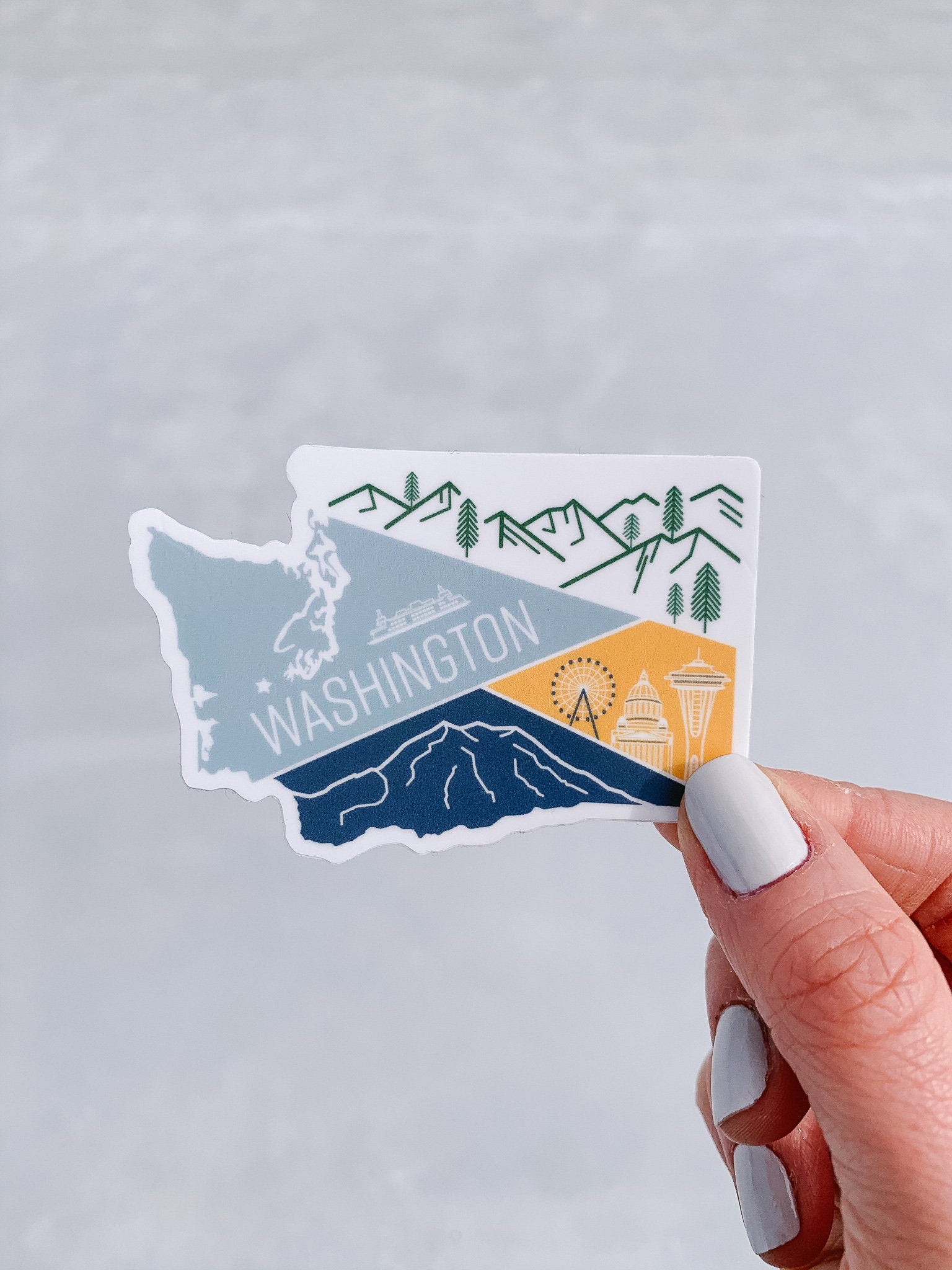 A vinyl sticker depicting a stylized map of Washington State with a mountain range, a ferry, and a city skyline.
