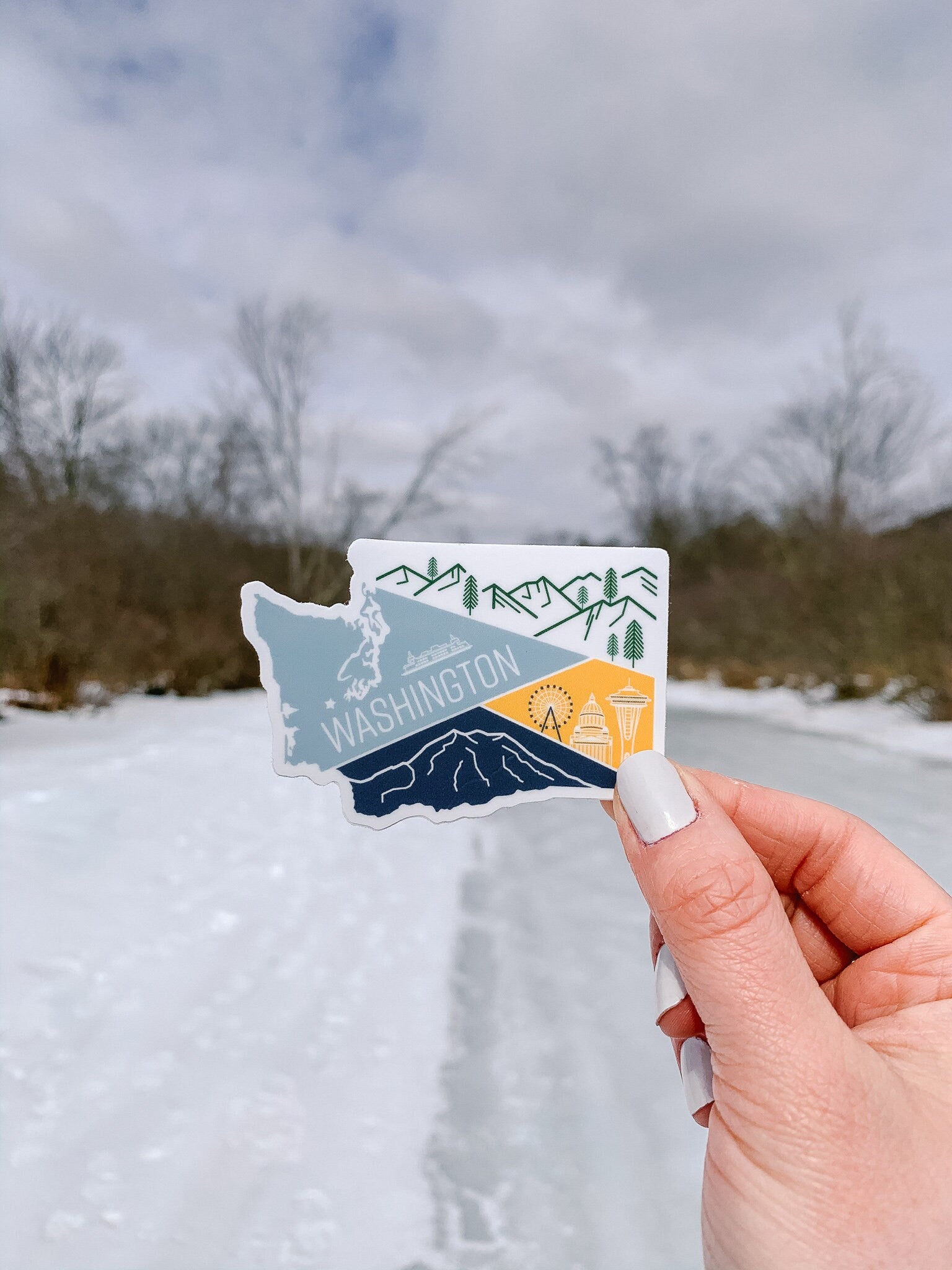 A vinyl sticker depicting a stylized map of Washington State with a mountain range, a ferry, and a city skyline.