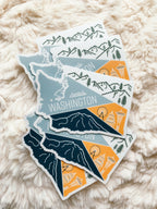 A vinyl sticker depicting a stylized map of Washington State with a mountain range, a ferry, and a city skyline.
