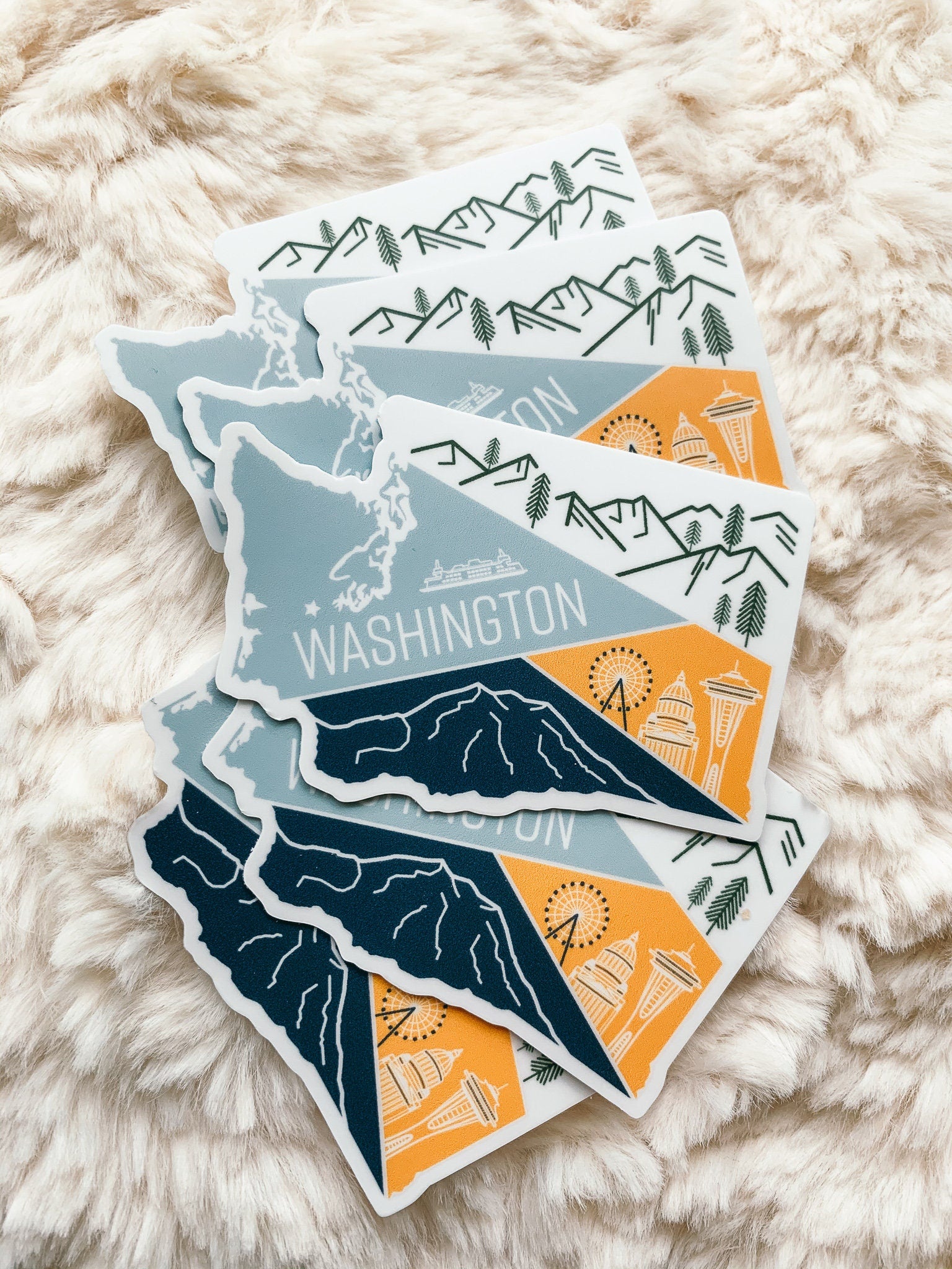 A vinyl sticker depicting a stylized map of Washington State with a mountain range, a ferry, and a city skyline.