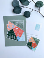 A postcard with an illustration representing Arizona's landscape, including a cactus and mountains, with a space for personalized messaging on the back.