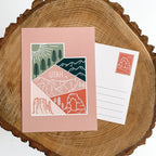 A postcard with an illustrated mountain range and the text 'UTAH' prominently featured. The design includes a mix of colors representing the landscape, and a logo is visible on the bottom.