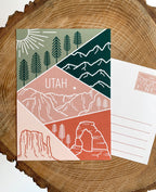 A postcard featuring a colorful illustration of Utah's landscape, including mountains and trees, with the word 'UTAH' prominently displayed.