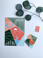 A postcard featuring a colorful illustration of Arizona's landscape, including mountains and cacti, with the text 'ARIZONA' at the top.