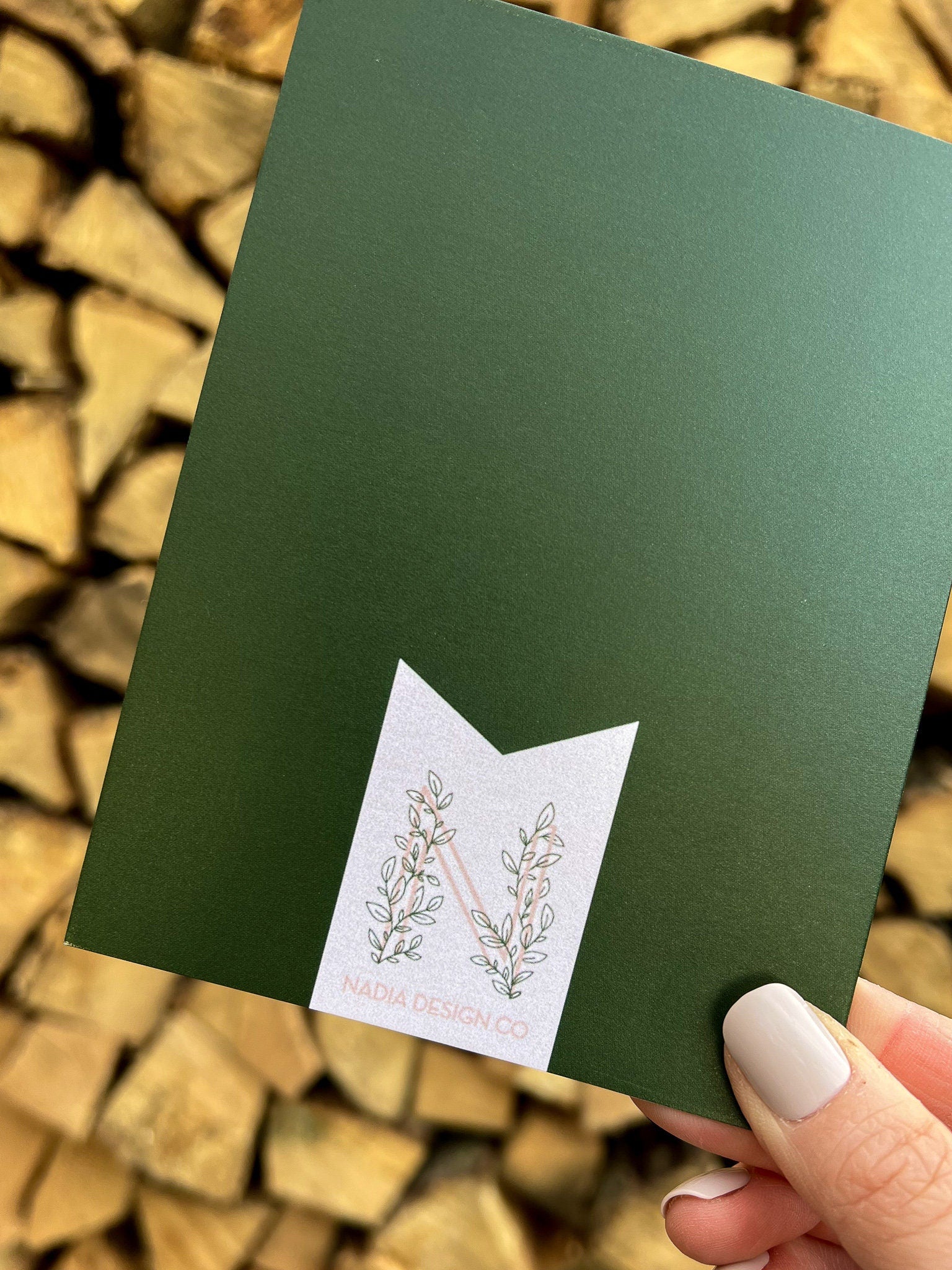 A hand holding a Christmas card with 'Peace on Earth' written on it, featuring a green background, a red bow, and stars.