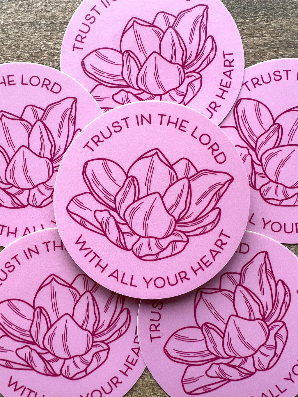 A set of pink vinyl stickers with a floral design and the text 'TRUST IN THE LORD WITH ALL YOUR HEART' written on them.