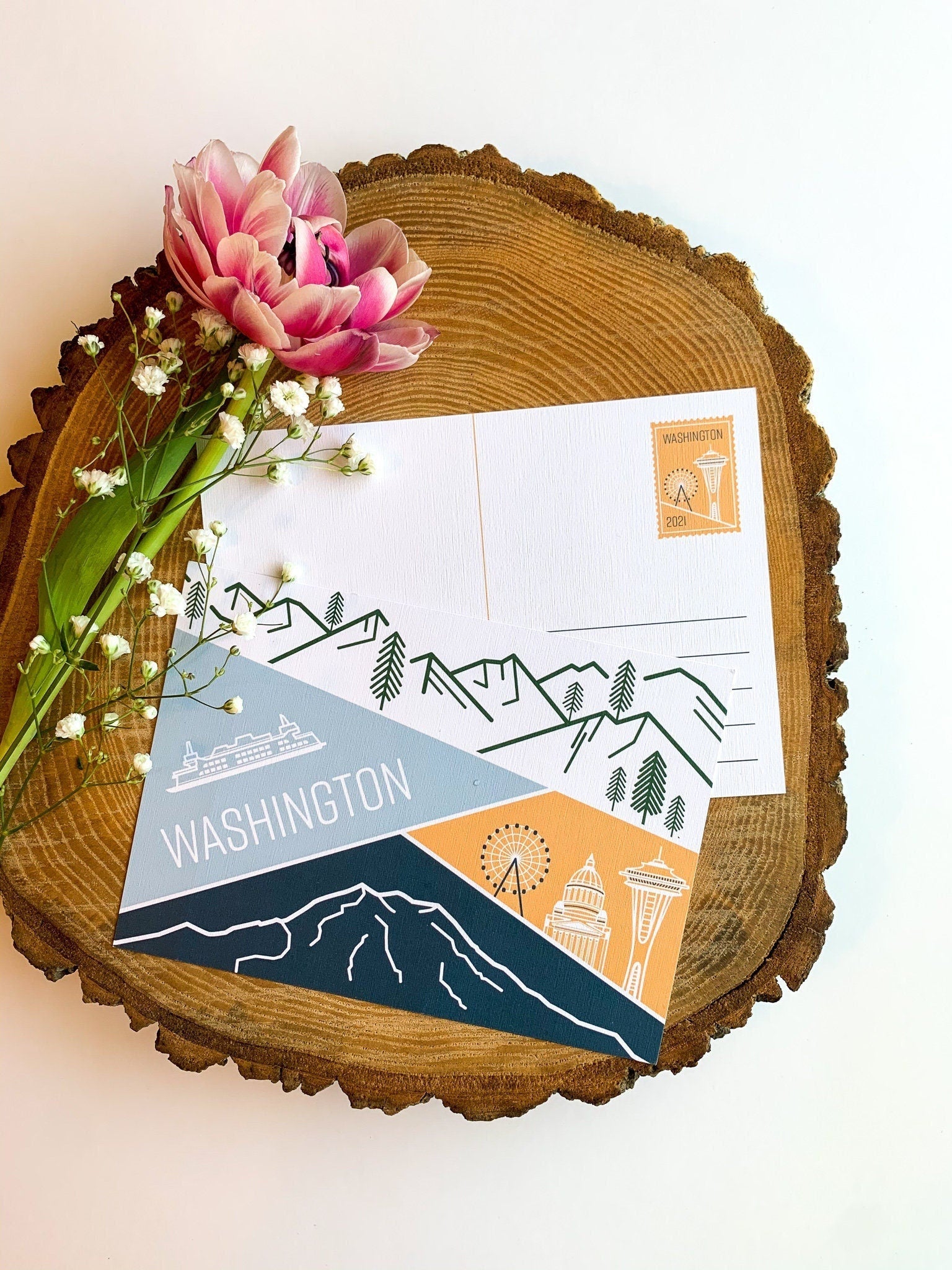 A postcard featuring illustrated landscapes and iconic symbols of Washington state, including mountains and the Seattle Space Needle.